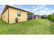 Side view of the backyard featuring a lawn, screened-in patio, and exterior of the house at 472 Pontevedra Rd, Davenport, FL 33837