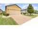 Paver driveway leading to a two-car garage with well-maintained lawn and landscaping at 472 Pontevedra Rd, Davenport, FL 33837