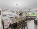 Open-concept dining room features a wooden table, chandelier and a view of the kitchen and living room at 718 Cr 467, Lake Panasoffkee, FL 33538
