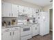 Bright kitchen features white appliances and cabinets, white subway tile backsplash, and wood-look floors at 718 Cr 467, Lake Panasoffkee, FL 33538