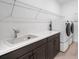 Well-lit laundry room with washer, dryer, countertop, sink, and storage at 12898 Harvest Rain Ave, Winter Garden, FL 34787