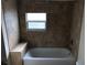 Well-lit bathroom with tiled walls, a window, and a bathtub with shower at 2915 Winter Lake Rd, Lakeland, FL 33803