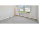 A bedroom with neutral carpet, and view of the backyard through two large windows at 5920 Bristle Oak St, Mount Dora, FL 32757
