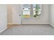 A bedroom with neutral carpet, and view of the backyard through two large windows at 5920 Bristle Oak St, Mount Dora, FL 32757