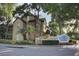 Beautiful townhome with lush landscaping in a well-maintained community, featuring mature trees and a stone entrance sign at 6300 Raleigh St # 102, Orlando, FL 32835