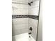 Modern bathroom featuring white-tiled walls, a gray tile accent, and updated bronze fixtures at 730 Barber Cir, Lakeland, FL 33803