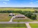 Aerial shot of home with an extended driveway, additional outbuildings, surrounded by picturesque farmland and scattered trees at 14365 Evans Ranch Rd, Lakeland, FL 33809