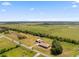 An aerial view showcasing a home with multiple buildings, all set against a backdrop of expansive green fields and distant horizon at 14365 Evans Ranch Rd, Lakeland, FL 33809