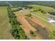Drone eye view of a rural property featuring a home, multiple outbuildings, surrounding greenery, and nearby pond at 14365 Evans Ranch Rd, Lakeland, FL 33809