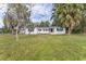 Quaint front exterior with a red front door surrounded by mature trees and a well-manicured lawn at 1816 W Lake Parker Dr, Lakeland, FL 33805