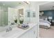 Bright bathroom with double sinks, white cabinets, quartz countertops, and a view into primary bedroom at 2076 Babbling Brook Blvd, Auburndale, FL 33823