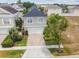 Aerial view of a two-story house with a white garage, driveway, and trees at 7523 Excitement Dr, Kissimmee, FL 34747