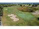 Aerial view of golf course with green fairways, trees, sand traps, and the blue flag at 7523 Excitement Dr, Kissimmee, FL 34747