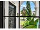 View through an arched window showcases the decorative front door and manicured landscaping at 740 Oak Shadows Rd, Kissimmee, FL 34747