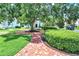 Lush front yard with a mature tree, brick pathway, and manicured landscaping at 740 Oak Shadows Rd, Kissimmee, FL 34747