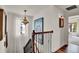 Hallway showcasing an ornate chandelier, stairway with rod iron railing and a view into a brightly lit bedroom at 740 Oak Shadows Rd, Kissimmee, FL 34747