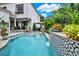 Backyard pool with waterfall feature, mature landscaping, and elegant home exterior at 740 Oak Shadows Rd, Kissimmee, FL 34747