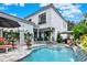 Beautiful backyard pool with patio seating, mature plants, and an elegant white home facade at 740 Oak Shadows Rd, Kissimmee, FL 34747