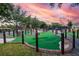Community putting green with artifical grass and manicured landscaping at sunset at 1430 Reunion Blvd, Reunion, FL 34747