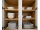 Organized kitchen cabinet with neat stacks of plates and bowls on wooden shelves at 1430 Reunion Blvd, Reunion, FL 34747