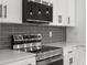 Modern stainless steel range and microwave with gray backsplash and white cabinets at 4116 Winona Dr, Orlando, FL 32812