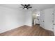 This is a spacious bedroom with wood floors, a ceiling fan and a view into the ensuite bathroom at 1161 Orangewood Ave, Deland, FL 32724