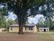 Charming single-story home with a metal roof, nestled on a large lot with mature trees and a storage shed at 2220 Woods Trl, Lakeland, FL 33809