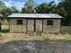 Outdoor shed features neutral siding, double doors, and a grey roof surrounded by trees at 2220 Woods Trl, Lakeland, FL 33809