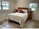 Bright main bedroom featuring wood-look flooring, windows, and decorative nightstands on either side of the bed at 2748 Cr 543, Sumterville, FL 33585