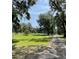 Expansive, lush green field with mature trees, framed by beautiful landscaping at 2748 Cr 543, Sumterville, FL 33585