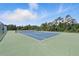 Well-maintained community tennis court with green and blue surface and tall net surrounded by tall trees at 413 Bay Leaf Dr, Poinciana, FL 34759