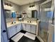 A beautifully renovated bathroom featuring dual sinks, new lighting, mirrors and a glass enclosed shower at 609 Linnet Ct, Poinciana, FL 34759