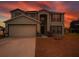 Two-story home featuring a neutral color palette and a two-car garage under a vibrant sky at dusk at 609 Linnet Ct, Poinciana, FL 34759