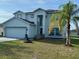 Charming two-story home featuring a well-manicured lawn and lush palm tree at 609 Linnet Ct, Poinciana, FL 34759