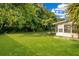 Lush backyard featuring a green lawn, mature trees, and an enclosed back porch at 1511 Avenue F Ne, Winter Haven, FL 33881