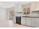 Bright kitchen boasts tile flooring, black dishwasher, light cabinets, and a view of the screened-in lanai at 1511 Avenue F Ne, Winter Haven, FL 33881
