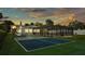 Inviting backyard featuring a screened pool, pickleball court, and lush lawn against a beautiful sky at 390 Windermere Dr, Lakeland, FL 33809