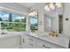 Bright bathroom featuring a dual sink vanity with gold fixtures, a large window, and a decorative mirror at 390 Windermere Dr, Lakeland, FL 33809