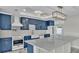 Bright kitchen features custom blue cabinets, marble countertops and flooring, stainless steel appliances, and pendant lighting at 390 Windermere Dr, Lakeland, FL 33809