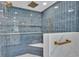Stunning walk-in shower featuring blue vertical tile, marble accents, gold fixtures, and built-in shelving at 390 Windermere Dr, Lakeland, FL 33809