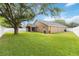 Large backyard with lush green grass, shade tree, and a covered lanai, perfect for outdoor living at 8360 Lake Amhurst Trl, Orlando, FL 32829