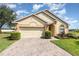Charming single-story home with a brick driveway, two-car garage, and manicured landscaping under a bright sky at 908 Andalusia Loop, Davenport, FL 33837