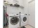 Well-lit laundry room with washer, dryer, shelving, and ample space for cleaning supplies at 908 Andalusia Loop, Davenport, FL 33837