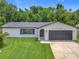 Charming home with a well-maintained lawn, mature trees and a dark gray roof at 34 Aaron Cir, Ormond Beach, FL 32174