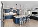Modern kitchen with an island, bar seating, navy cabinets, stainless steel appliances, and wood-look floors at 10298 Sw 96Th Loop, Ocala, FL 34481