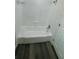 A bathroom with a standard white bathtub surrounded by white tile, next to the door at 1923 Beechwood Dr, Lakeland, FL 33803