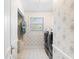 Charming laundry room with floral wallpaper, white tile floors, and modern washer and dryer at 2110 Reaney Rd, Lakeland, FL 33803