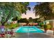 Outdoor pool surrounded by lush greenery and ambient lighting, creating a tranquil atmosphere at dusk at 2110 Reaney Rd, Lakeland, FL 33803