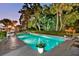 Inviting pool area featuring manicured landscaping, palm trees, and illuminated pool at dusk at 2110 Reaney Rd, Lakeland, FL 33803