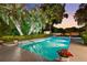 Backyard pool at dusk surrounded by lush landscaping and palm trees, creating a tranquil oasis at 2110 Reaney Rd, Lakeland, FL 33803